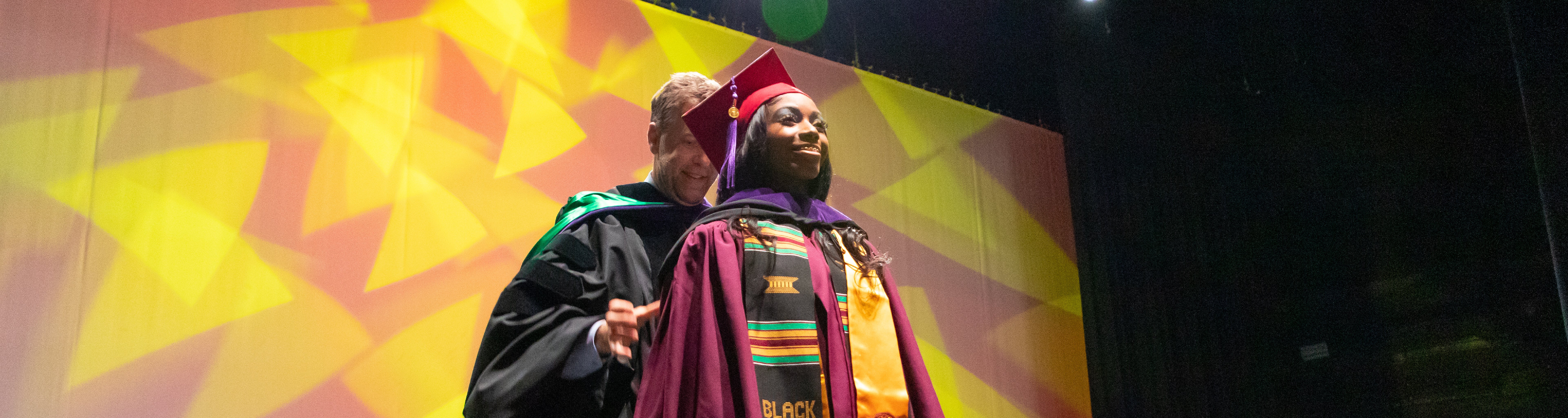 Student on stage smiling while receiving JD degree during ASU Law's convocation 