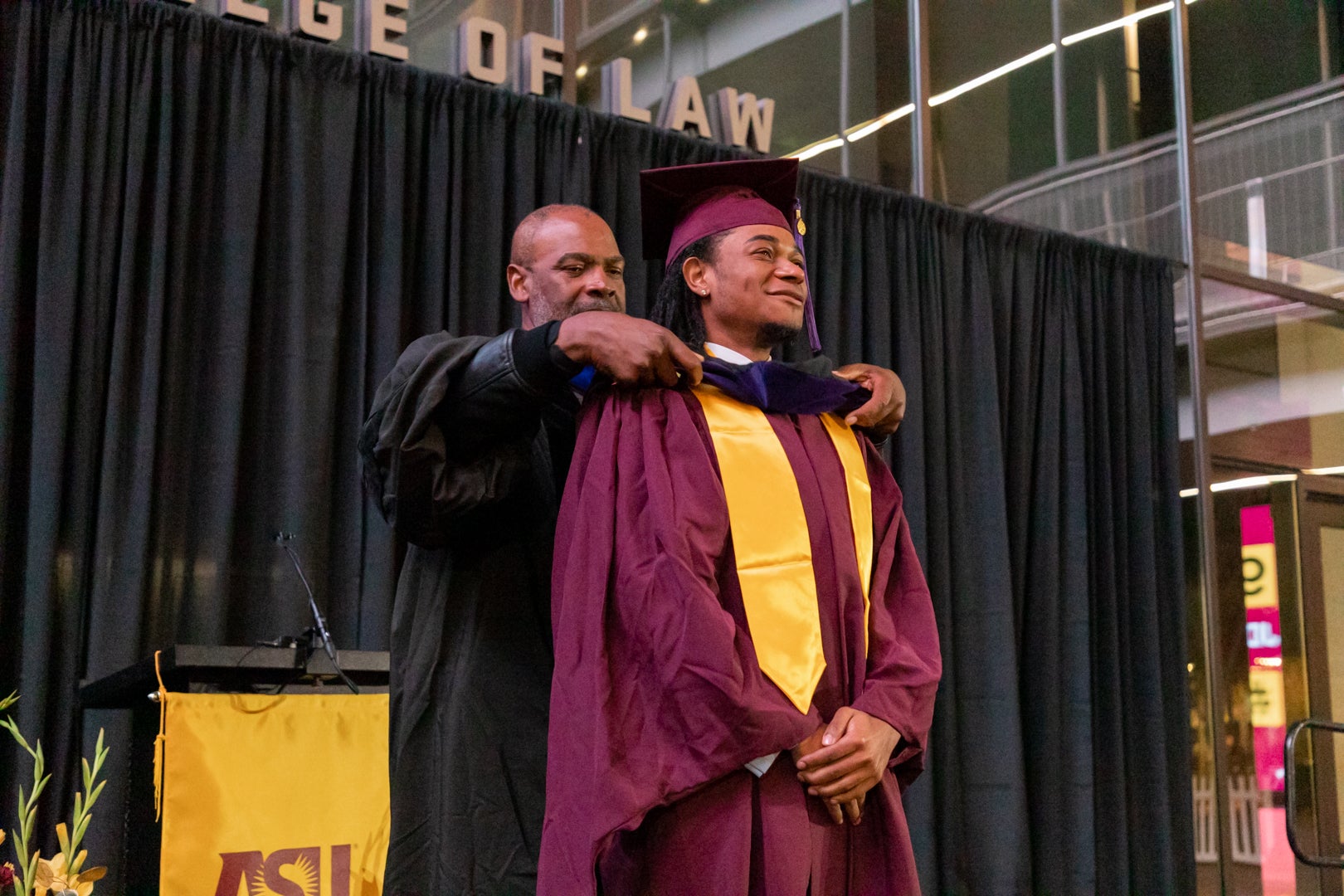 Don Gibson putting a robe on a MLS graduate student during the ASU Law convocation ceremony.