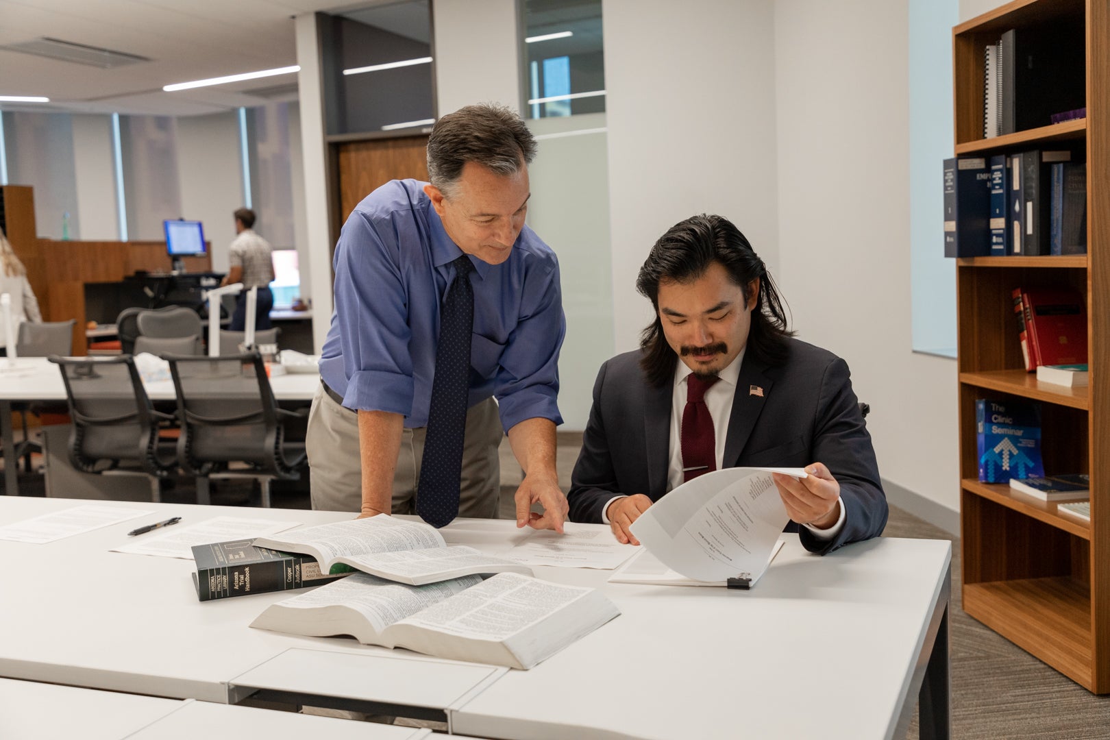 JD student looking over a document with Clinical Professor of Law, Art Hinshaw. The student is lifting a page and Professor Hinshaw is pointing at the page.