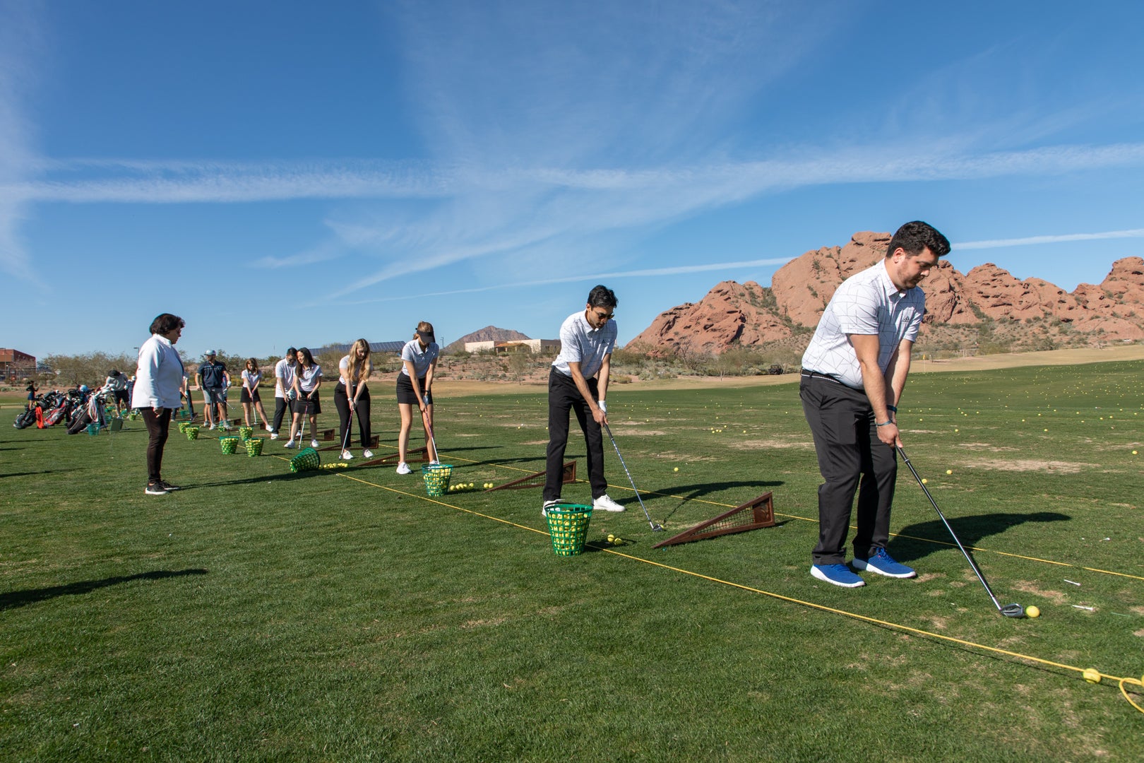 ASU Law students participating in the Grads to Golf program. Student lined up about to hit a gold ball with a golf club on the driving range.