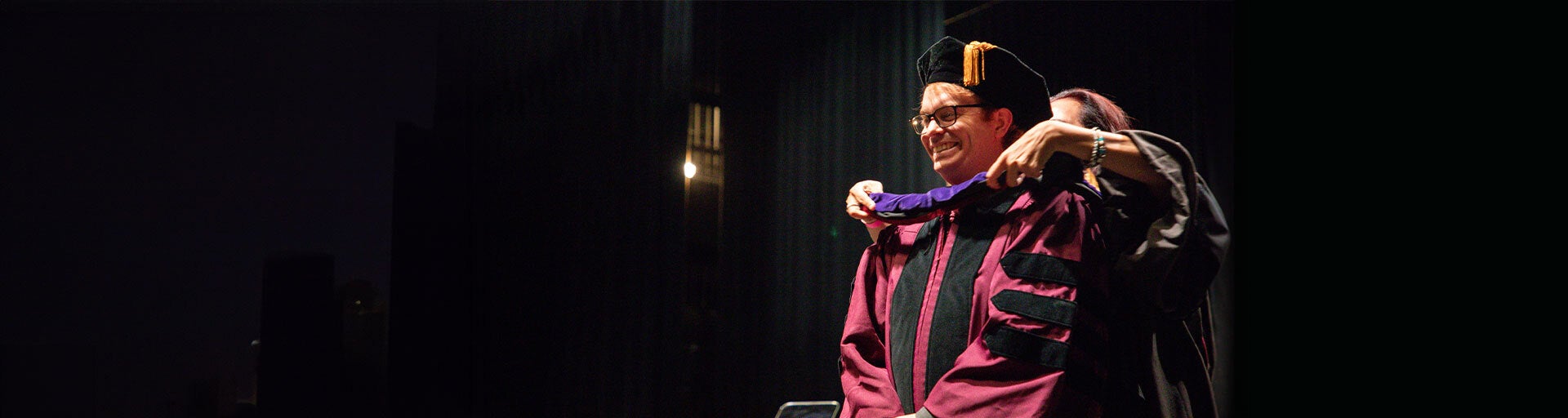 Professor Kate Rosier placing ceremonial graduation robe on Juris Doctor graduate student.
