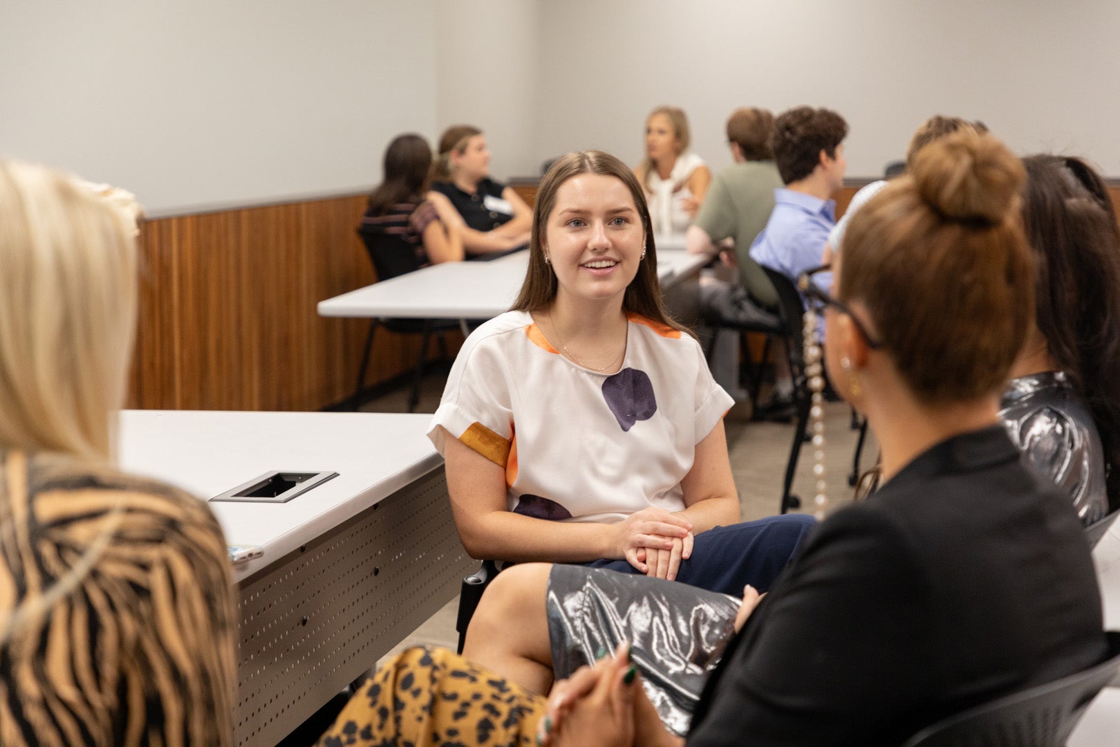 An ASU Law student sitting in a classroom talking to three other students. 
