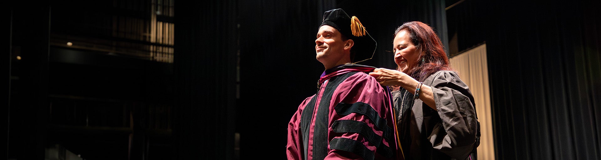 Professor Rossier plaacing a robe on a Juris Doctor, JD student during the Spring 2023 Convocation ceremony.
