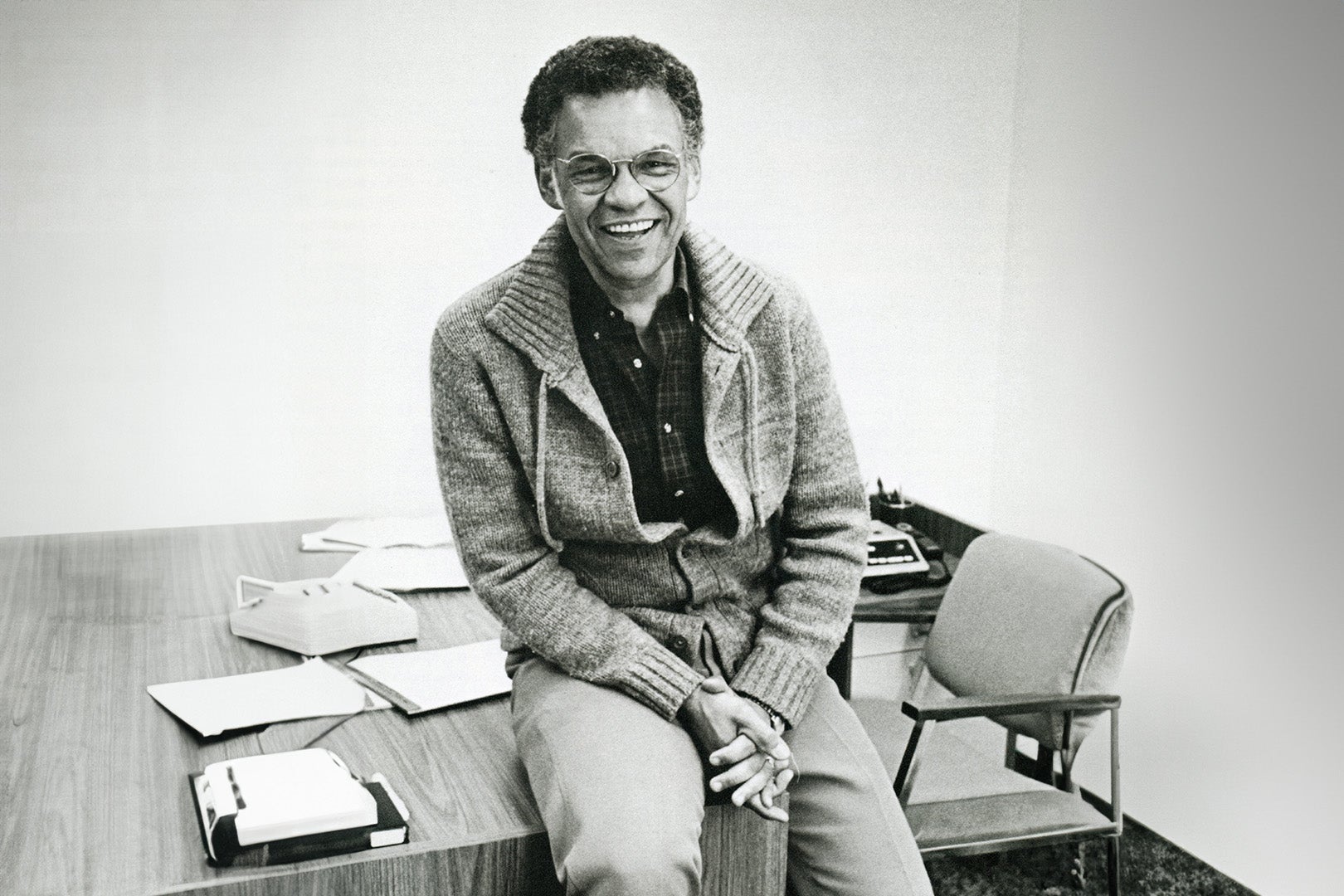 Black and white photo of John P. Morris sitting on his desk smiling.