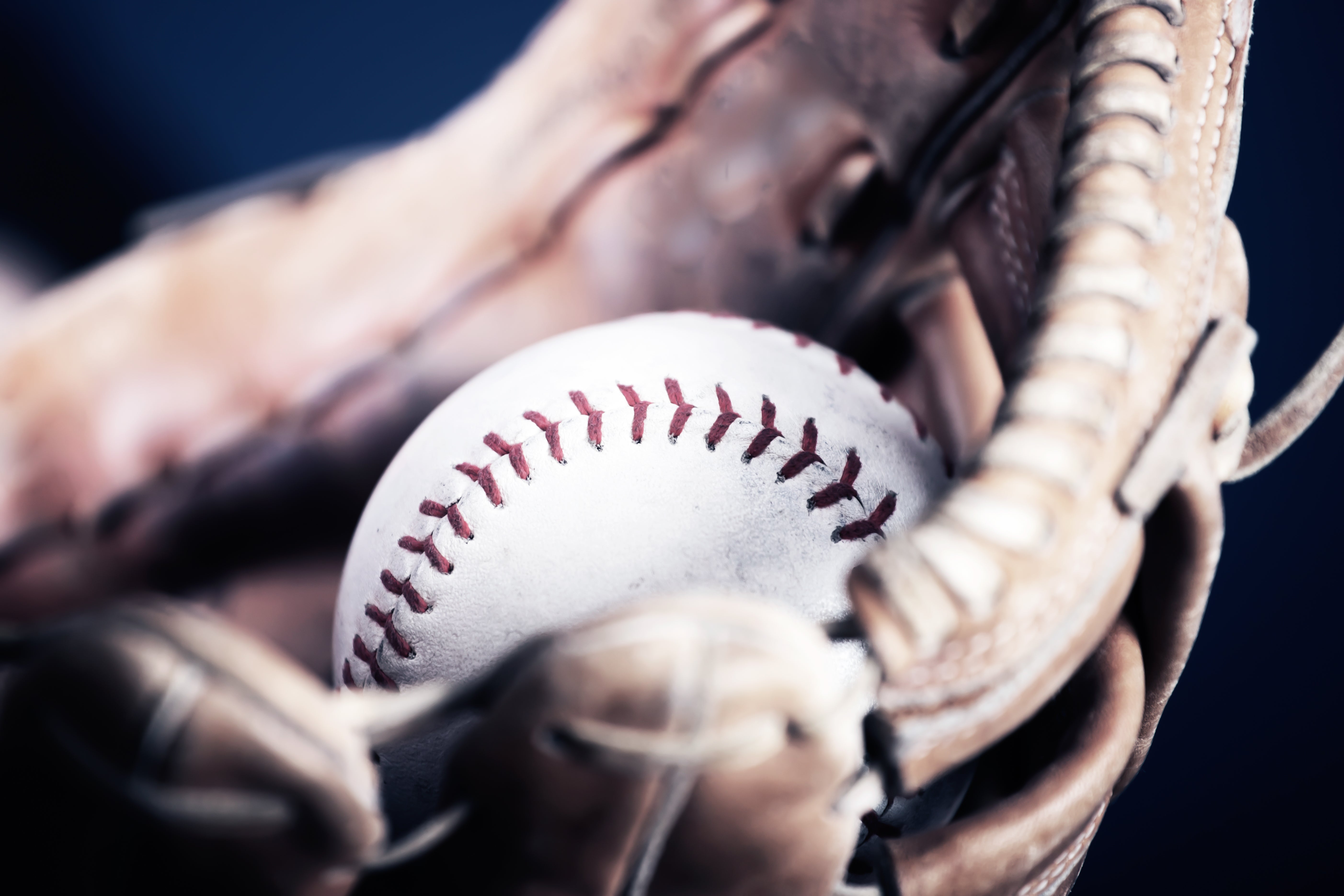Close-up of a baseball glove holding a white baseball. 