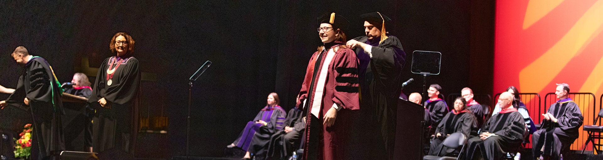 A professor placing the ceremonial robe on a JD graduate student during the Spring 2024 Convocation ceremony.