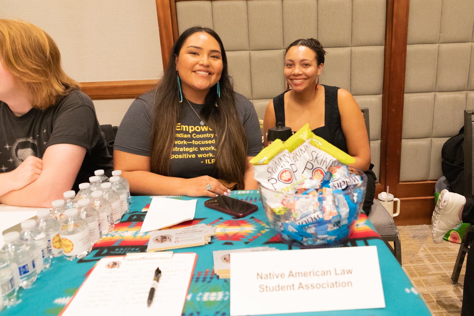 Two ASU Law Indian Legal sitting in front of the Native American Law Student Association booth at the ASU Law student organization fair. 