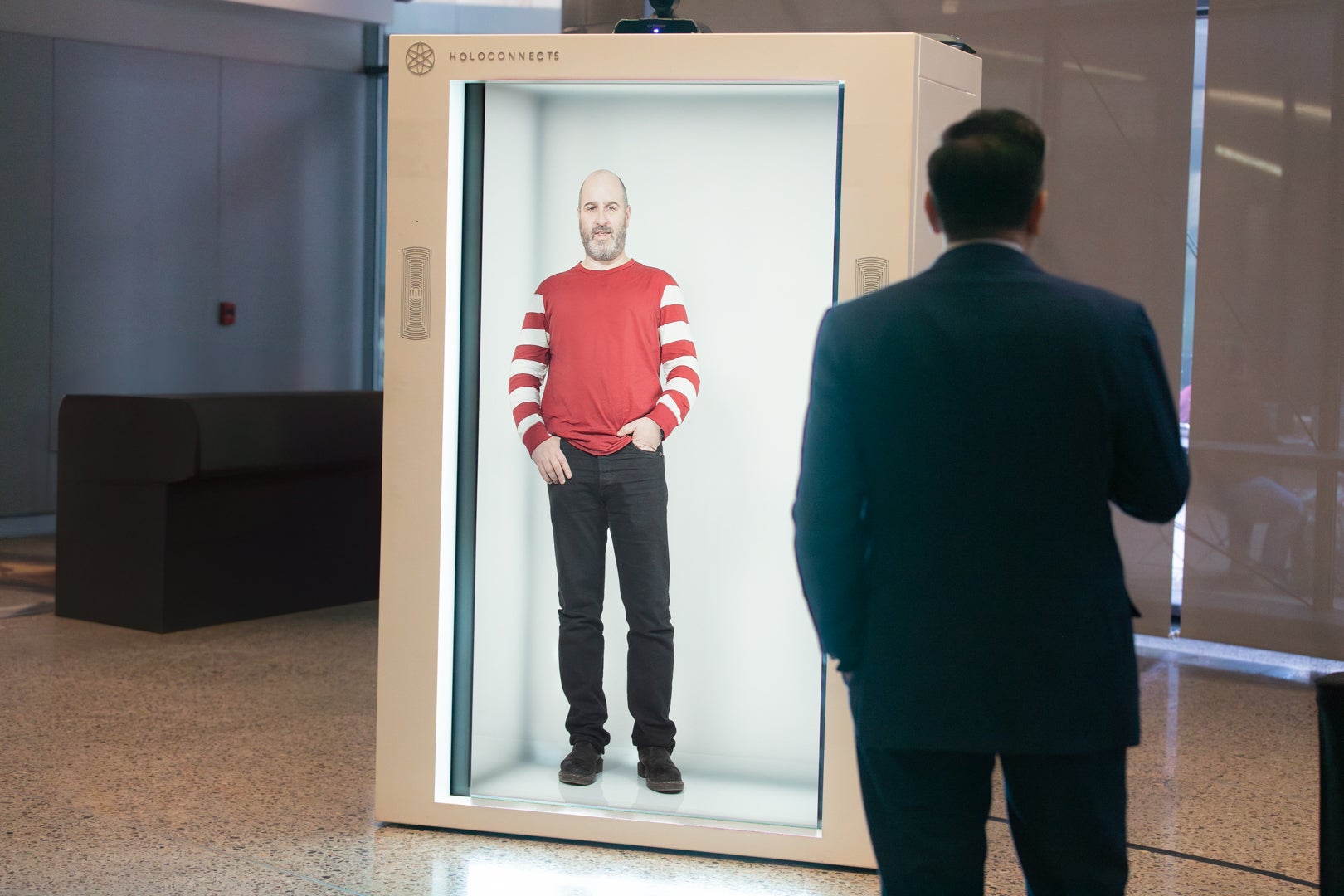 Guest speaker standing in a hologram box at ASU Law, talking to a man in a suit. 