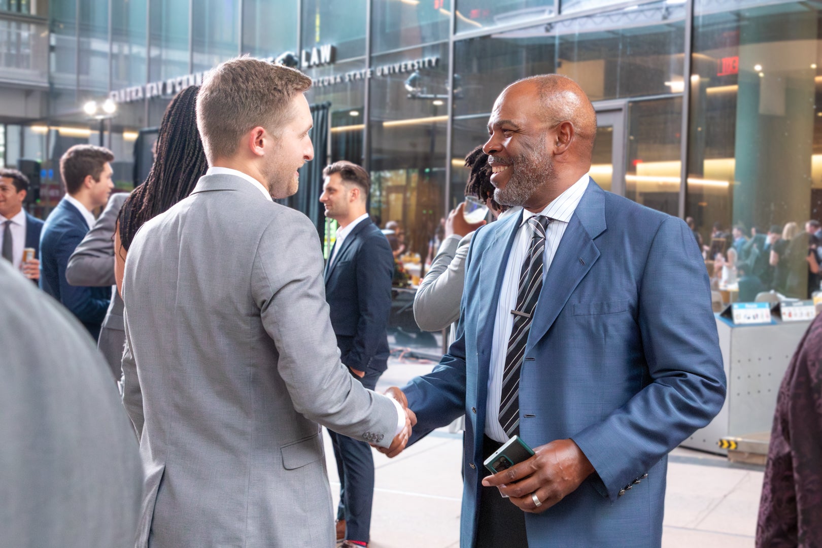 Professor Don Gibson shaking hands with an ASU Law student during a graduation event.