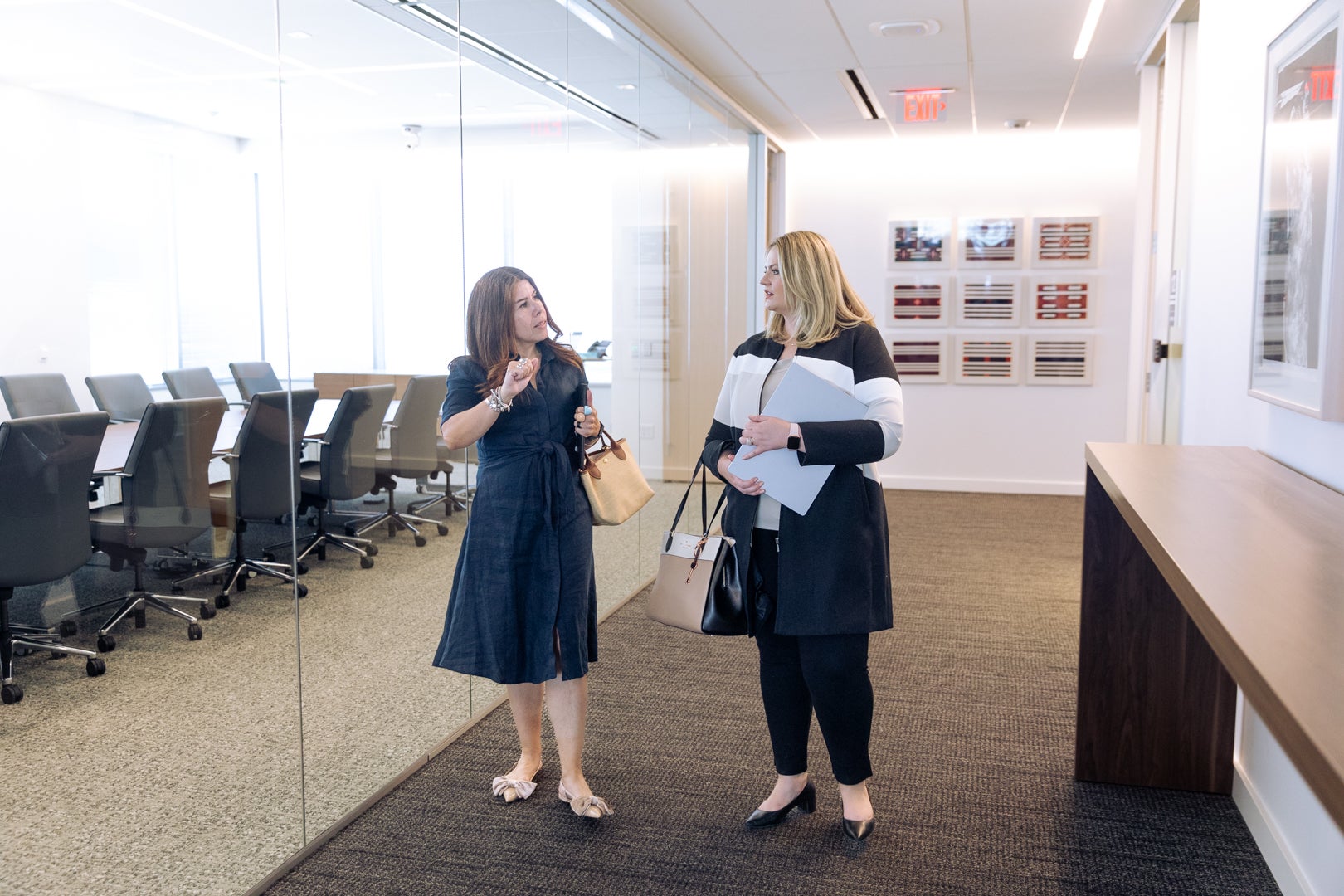 Two ASU Law students walking in a local law firm while holding bags and paper.