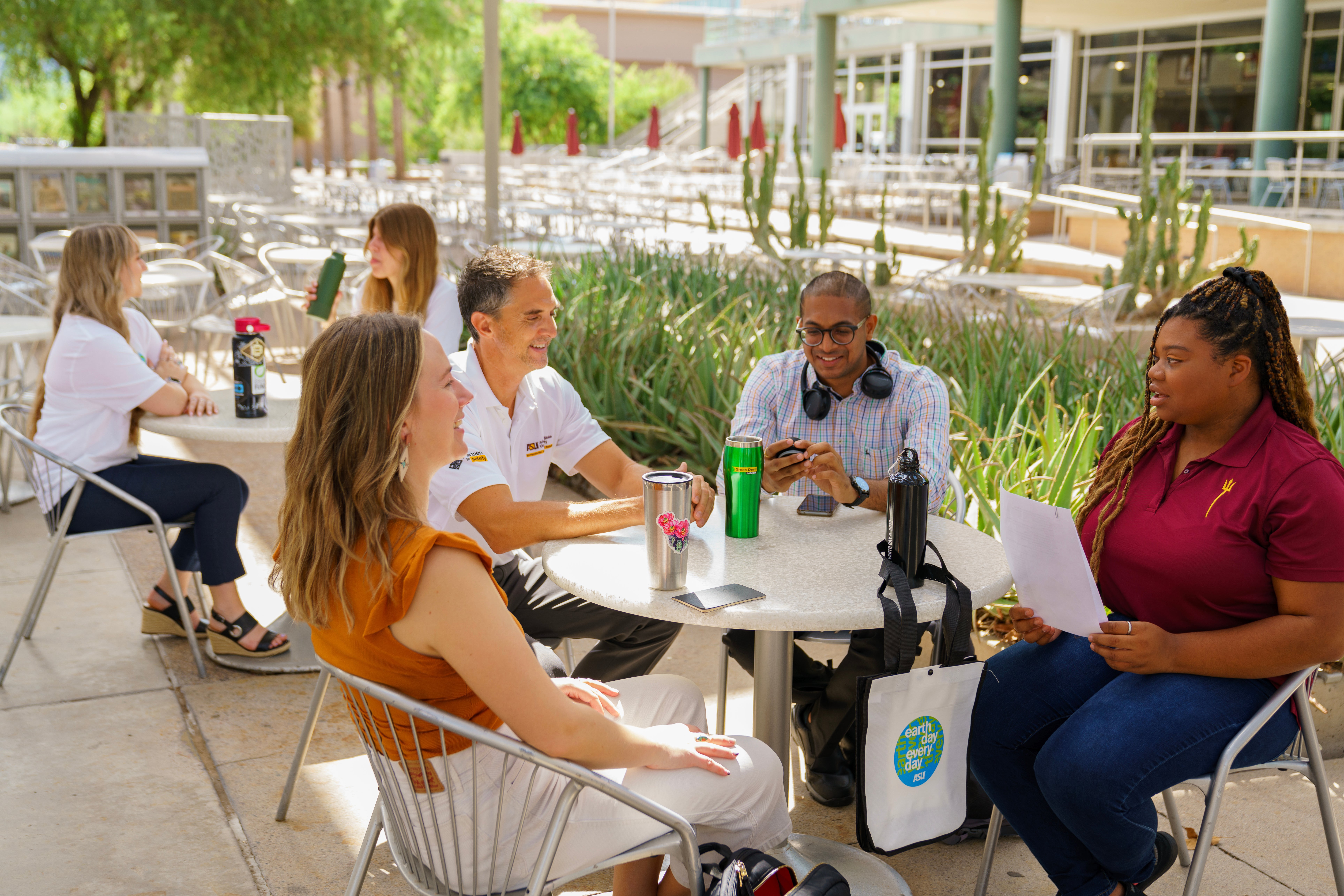 Four ASU students sitting at a table in a pavilion on Tempe campus.