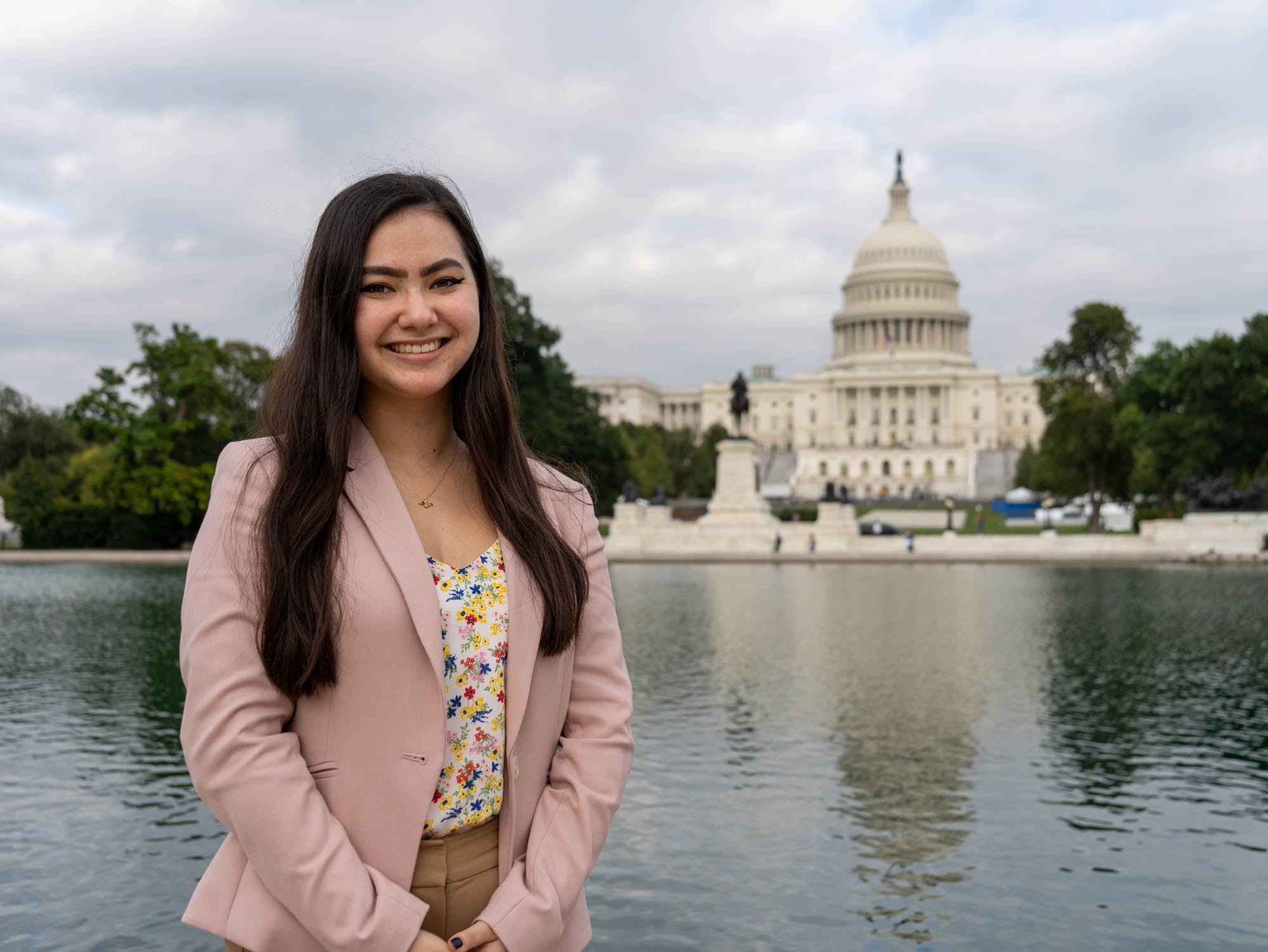 ASU Law Indian Legal student standing in front of the US Capital while wearing a light pink suit. 