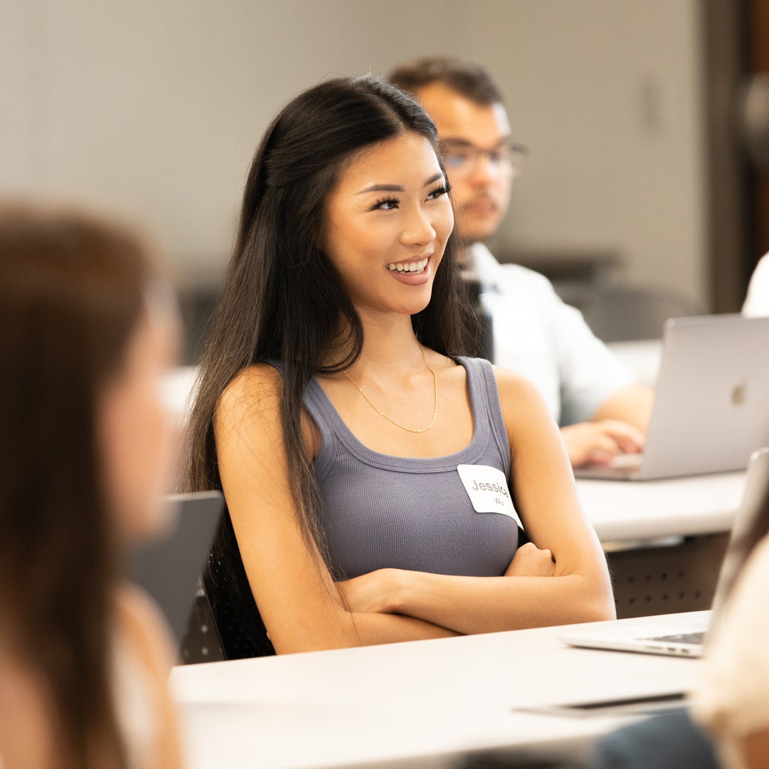 A student smiles while listening attentively at the 2023 Advance Orientation