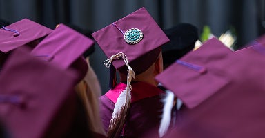A student dressed in their regalia from behind at a convocation ceremony
