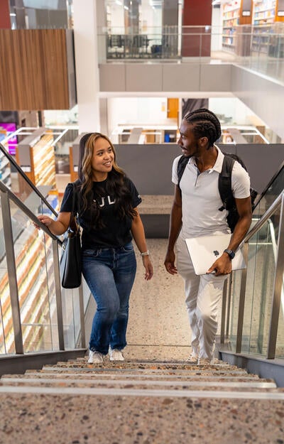 Two students talking ascend a staircase in the ASU Law Library
