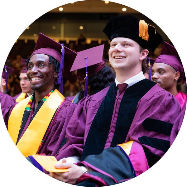 Students smile while attending their graduation ceremony.