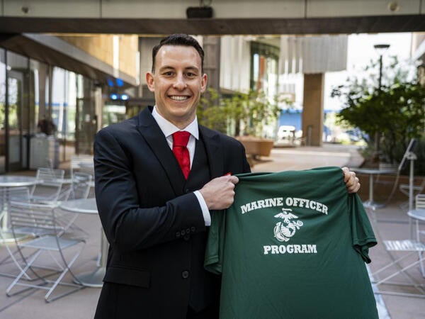 Donald Bryson Griffith smiling while holding up a green Marine Officer Program t-shirt