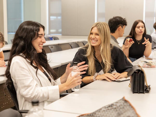 Two students talking and laughing in classroom at Sandra Day O'Connor College of Law