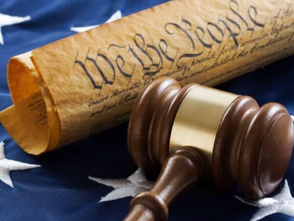 The Preamble and brown gavel laying across the blue stars on the American flag.