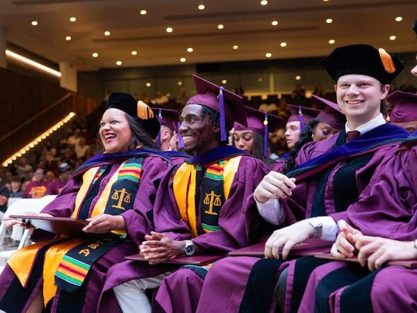 ASU Law students smile and laugh while attending their graduation ceremony.