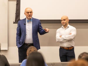 Two men in suits teach in a classroom.