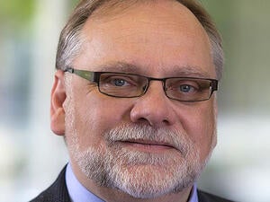 A man with glasses smiles for the camera.