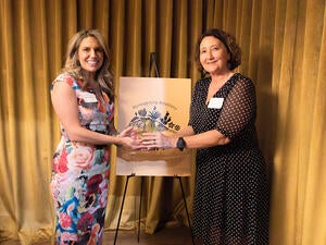 Two women pose with an award.