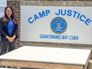 A brunette woman poses in front of a sign.