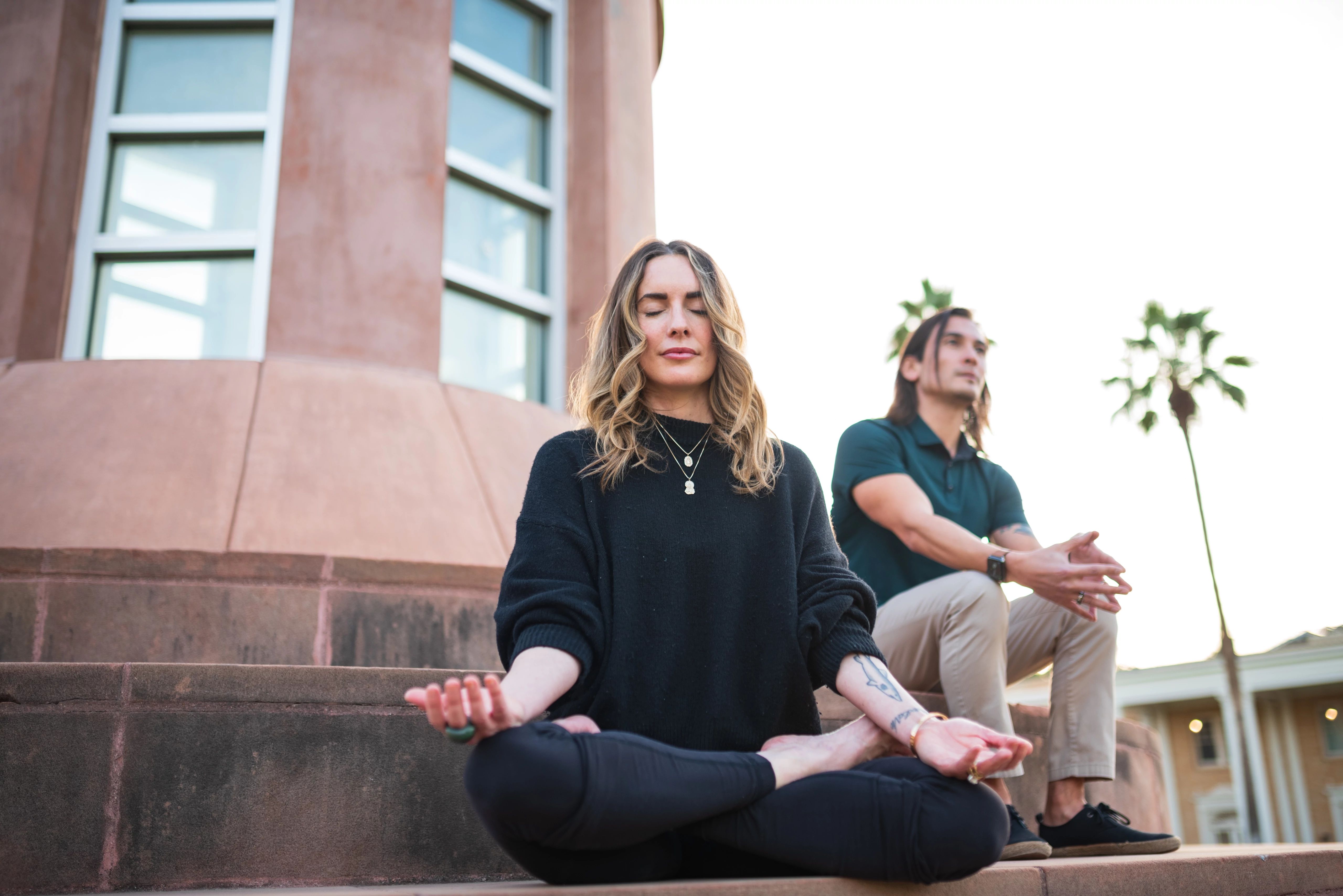 Photo of ASU Courtney Lively and Danielle Knotts from Enterprise Marketing Hub sitting and meditating in front of the ASU Hayden Library.
