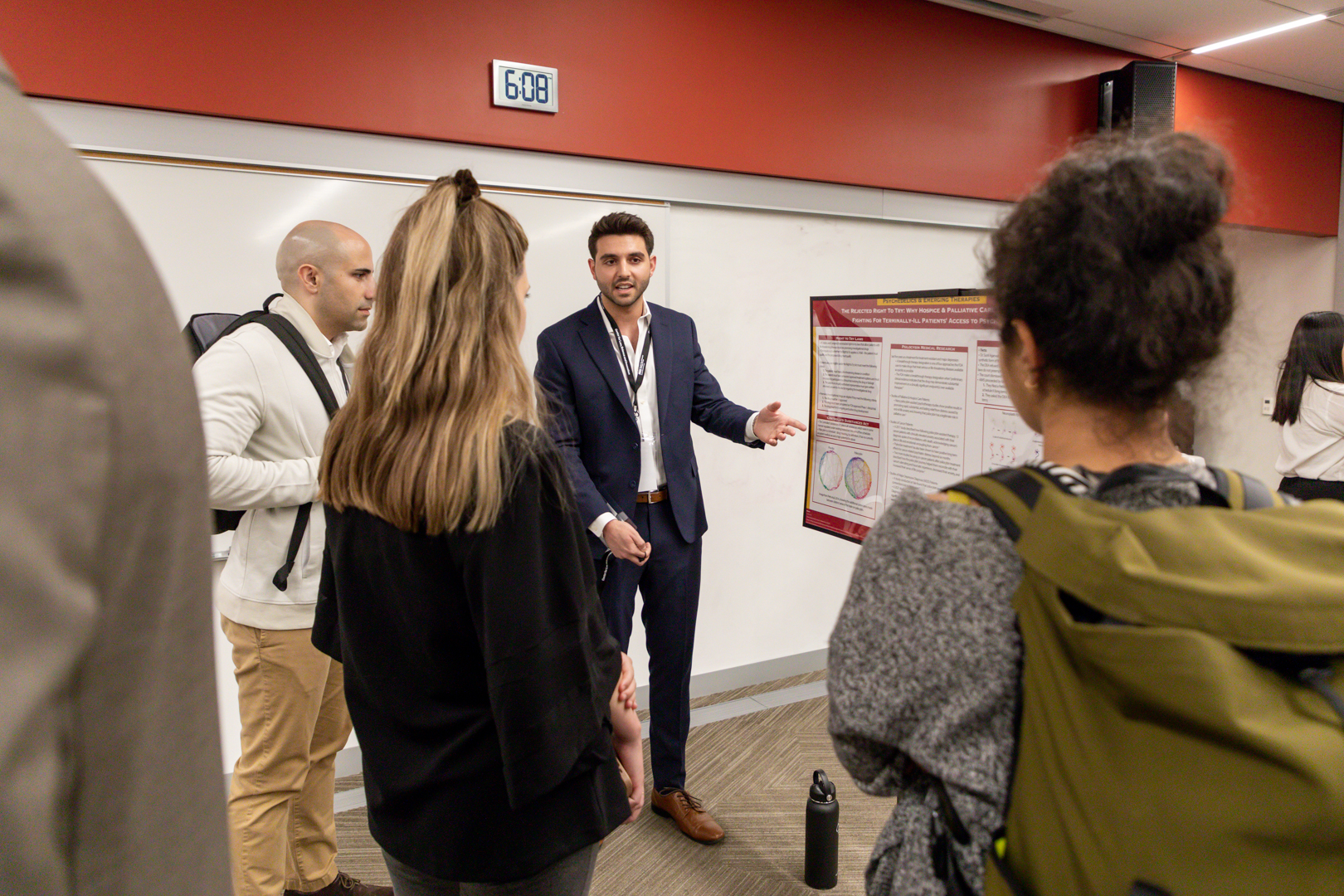 A LSI student giving a presenation at the Governance of Emerging Technologies and Science (GETS) conference. He is surrounded by other students and members of the conference.