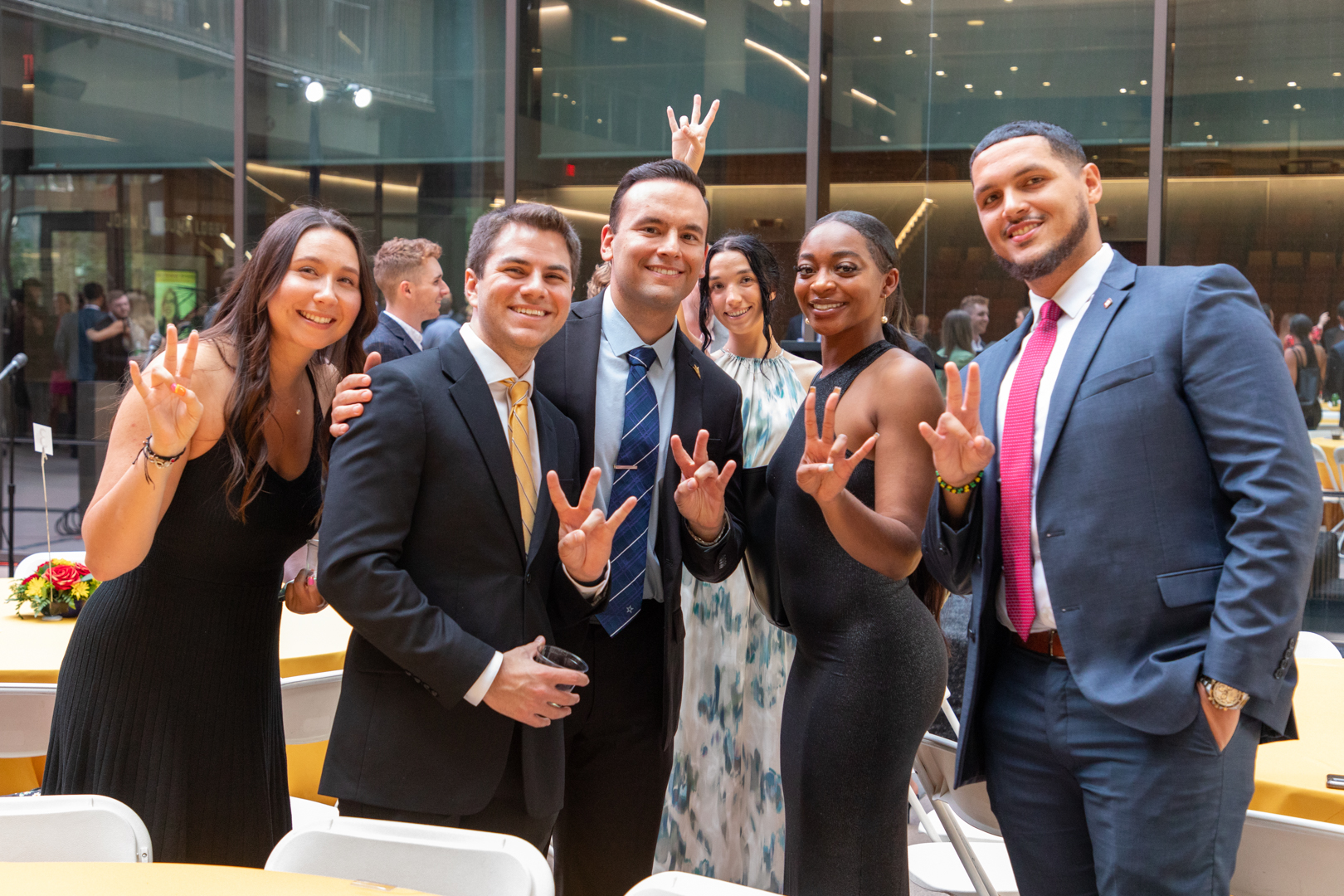 Assistant Dean and Executive Director of SLB Aaron Hernandez and students holding up a pitchfork with their hands at the graduation dinner.